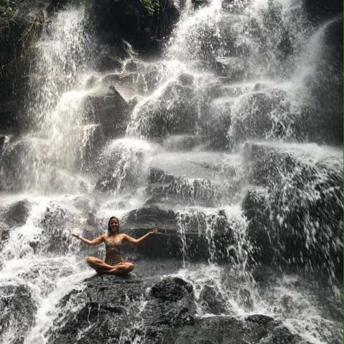Estela Kun sitting on the rocks in a waterfall