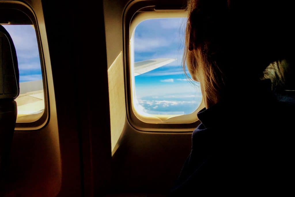 traveler looking out the window of an airplane in flight